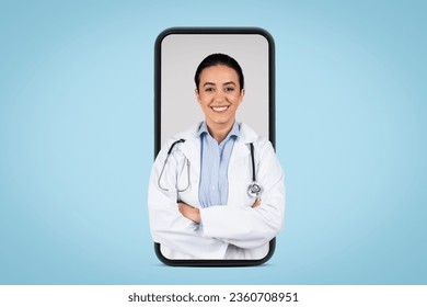 Young brazilian woman doctor in white uniform posing with stethoscope and folded arms in huge cellphone screen, blue background, banner. Medical services concept - Powered by Shutterstock