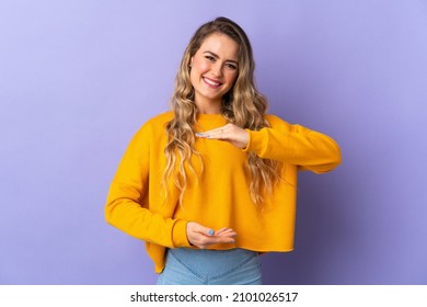 Young Brazilian woman isolated on purple background holding copyspace imaginary on the palm to insert an ad