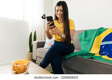 Young Brazilian Woman Using Cellphone To Invite Friends To Watch Soccer Game At Her Home.