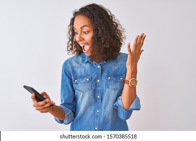 Young brazilian woman using smartphone standing over isolated white background very happy and excited, winner expression celebrating victory screaming with big smile and raised hands