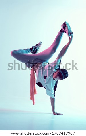 Young breakdancer guy stands on one hand dancing hip-hop in neon light. Dance school poster