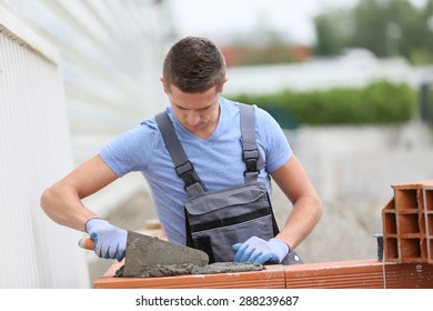 Young Brick Layer Working Outside On Brick Wall Construction