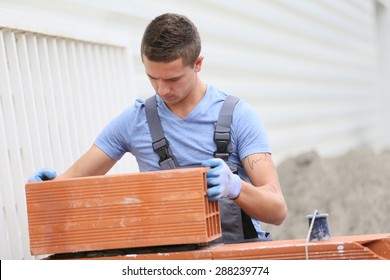 Young Brick Layer Working Outside On Brick Wall Construction