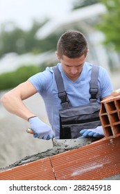 Young Brick Layer Working Outside On Brick Wall Construction