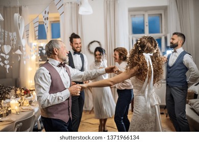 A young bride dancing with grandfather and other guests on a wedding reception. - Powered by Shutterstock