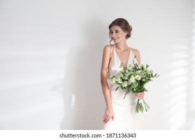 Young bride wearing wedding dress with beautiful bouquet on light background. Space for text - Powered by Shutterstock