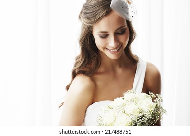 Young bride in wedding dress holding bouquet, studio shot   - Powered by Shutterstock