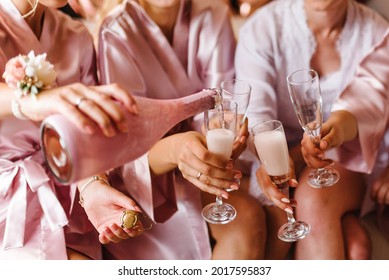 Young bridesmaids clinking with glasses of champagne in hotel room. Closeup photo of cheerful girls celebrating a bachelorette party. Females have toast with wine.