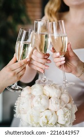 Young Bridesmaids Clinking With Glasses Of Champagne In Hotel Room. Closeup Photo Of Cheerful Girls Celebrating A Bachelorette Party. Females Have Toast With White Wine.