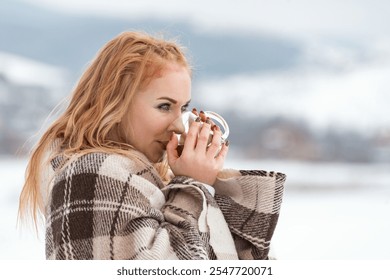 Young bright red-haired woman drinks hot chocolate cocoa tea outdoors winter day. Portrait of beautiful ginger hair girl against winter landscape - Powered by Shutterstock