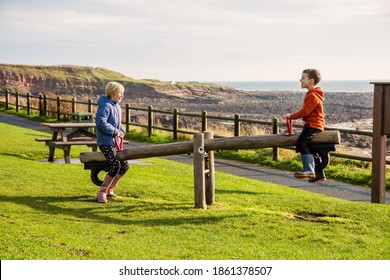 A young brother and sister playing on a seesaw in a park at Crail, Fife, Scotland. This park is on the coastal trail and is in a very beautiful location.