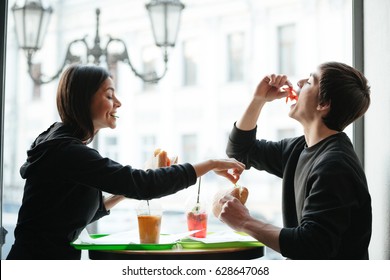 Young Brother And Sister Sitting In Cafe And Eating Burgers