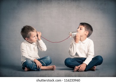 Young brothers talking with tin can telephone on grunge background. - Shutterstock ID 116233960
