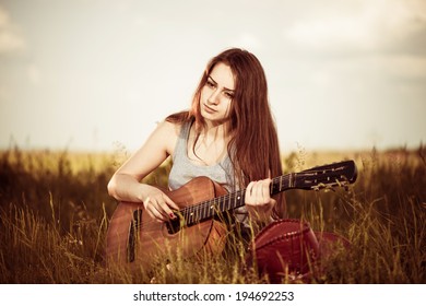 Young Brunet Woman Playing Sad Song At Spring Meadow Grass