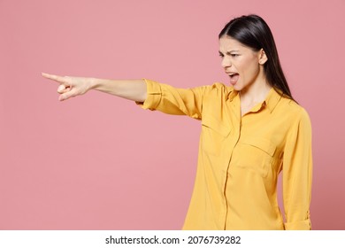Young brunette angry sad serious strict latin student woman 20s wearing yellow casual shirt pointing index finger aside commanding scream shout isolated on pastel pink color background studio portrait - Shutterstock ID 2076739282