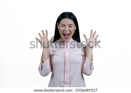 Young brunette asian woman is screaming out loud. Korean girl with her hands up. Isolated on white background.