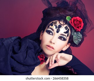 Young brunette in black dress and with red rose in her hair.