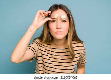 Young Brunette In Casual Clothing Having Sight Problems And Looking Confused While Wearing Glasses In A Studio