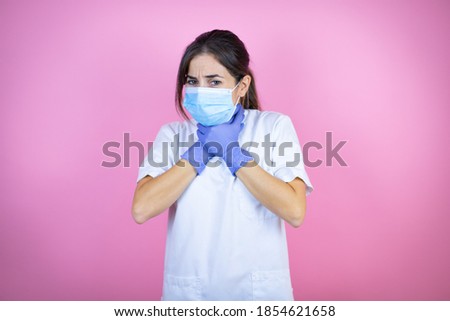 Young brunette doctor girl wearing nurse or surgeon uniform with latex gloves and mask over isolated pink background touching painful neck, sore throat for flu, clod and infection