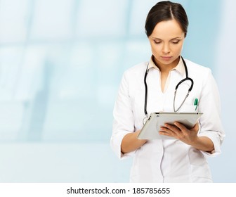 Young Brunette Doctor Woman Taking Notes On Tablet Pc 