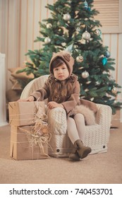 Young brunette dolly lady girl stylish dressed cozy warm winter gray jacket with fur posing sitting standing in studio close to Christmas New Year tree and presents