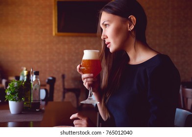 Young brunette drinking a beer in a restaurant