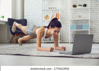Young brunette exercising at home watching fitness training video on laptop computer. Side view. - Shutterstock ID 1776413903