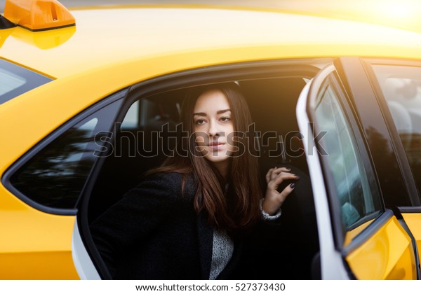 Young\
brunette girl in backseat of taxi with open\
door