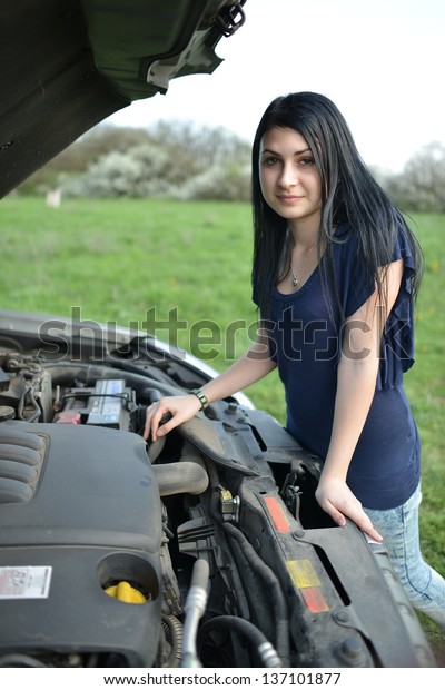 young
brunette girl with a broken car with open
hood