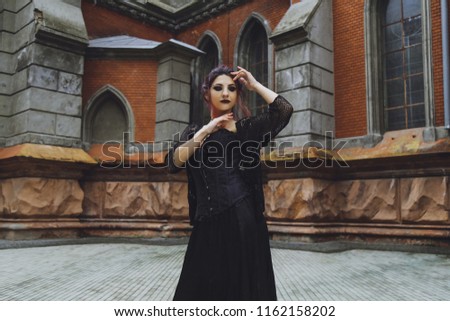 Young brunette girl in gothic style on a background architecture
