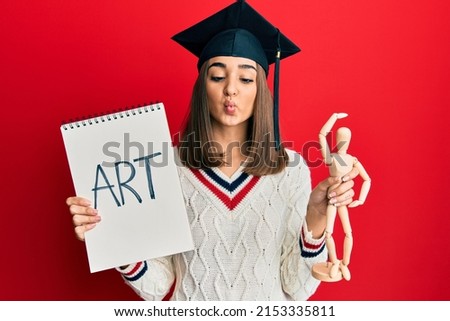 Young brunette girl graduated on art making fish face with mouth and squinting eyes, crazy and comical. 