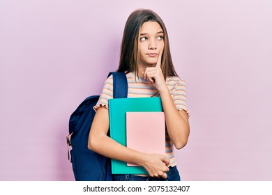 Young brunette girl holding student backpack and books serious face thinking about question with hand on chin, thoughtful about confusing idea  - Powered by Shutterstock