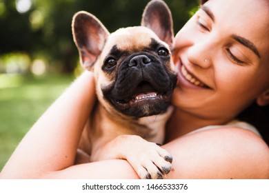 Young brunette girl with a little puppy french bulldog. Play and have fun in the summer park. - Shutterstock ID 1466533376