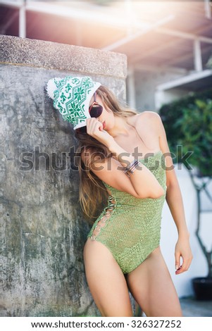young brunette girl posing in swimsuit sunglasses at the bottom of an empty swimming pool sneakers.young hipster stylish beautiful girl listening to music, mobile phone, headphones,