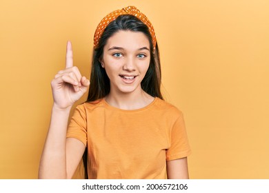 Young brunette girl wearing casual orange t shirt pointing finger up with successful idea. exited and happy. number one.  - Powered by Shutterstock