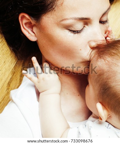 young brunette happy mother holding toddler baby son, breast-fee