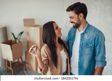 Young brunette lady looking at her male partner with love and affection while holding metal keys from a house
