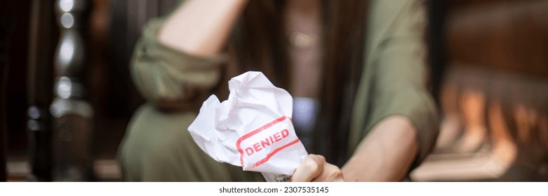 Young brunette long hair girl cries hysterically after being denied a mortgage loan. Depressive sad eviction female millenial holding rejection document copy space banner - Shutterstock ID 2307535145