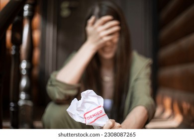 Young brunette long hair girl cries hysterically after being denied a mortgage loan. Depressive sad eviction female millenial holding rejection document copy space banner - Shutterstock ID 2308087265