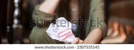 Young brunette long hair girl cries hysterically after being denied a mortgage loan. Depressive sad eviction female millenial holding rejection document copy space banner