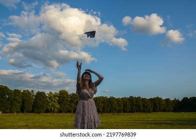 Young Brunette Smiling Woman Throwing Paper Plane In The Air. Hope And Dream Concept 