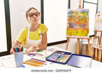 Young brunette teenager at art studio looking at the camera blowing kiss air being lovely  love expression  