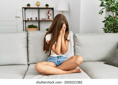 Young brunette teenager sitting on the sofa at home with sad expression covering face with hands while crying. depression concept.  - Powered by Shutterstock