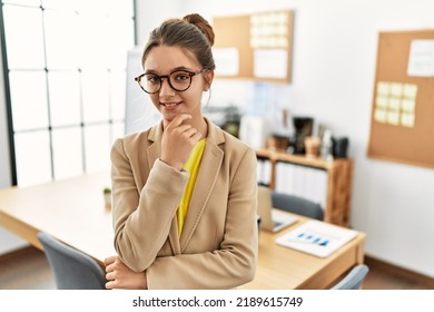 Young Brunette Teenager Wearing Business Style At Office Looking Confident At The Camera Smiling With Crossed Arms And Hand Raised On Chin. Thinking Positive. 
