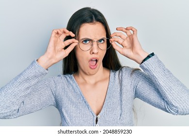 Young Brunette Teenager Wearing Glasses In Shock Face, Looking Skeptical And Sarcastic, Surprised With Open Mouth 