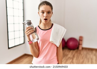 Young Brunette Teenager Wearing Sportswear Holding Water Bottle In Shock Face, Looking Skeptical And Sarcastic, Surprised With Open Mouth 