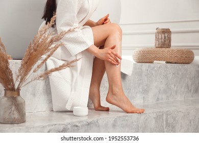 Young brunette woman applying body scrub or cream on skin sitting in luxury bathroom. - Powered by Shutterstock