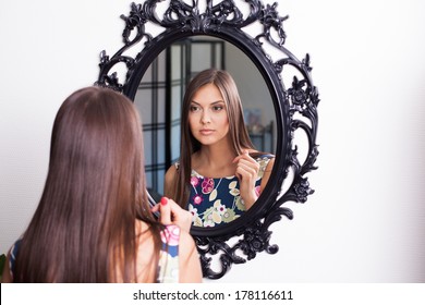 Young brunette woman in beauty salon looking at herself in mirror
