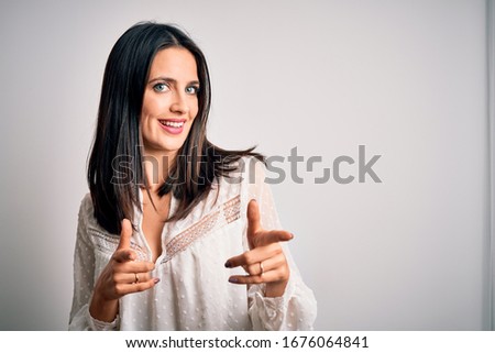 Young brunette woman with blue eyes wearing casual t-shirt over isolated white background pointing fingers to camera with happy and funny face. Good energy and vibes.