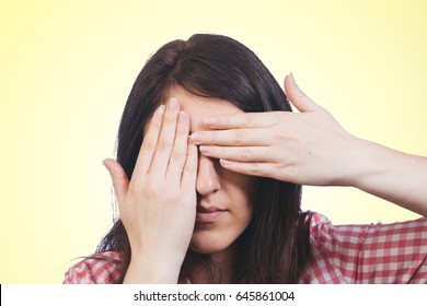 Young brunette woman covers her eyes with her hands